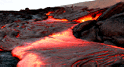 Glowing, reddish-orange lava flowing on the surface at Hawai`i Volcanoes National Park